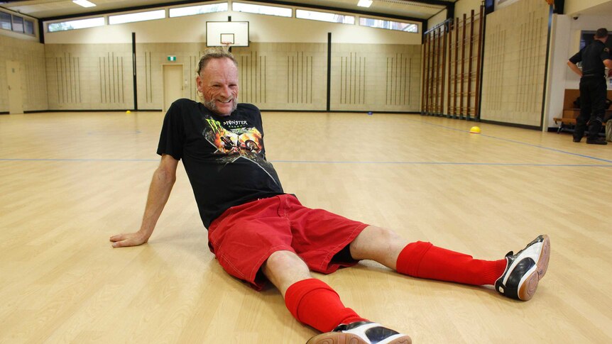 Tim Dixon sitting on a futsal court in Launceston