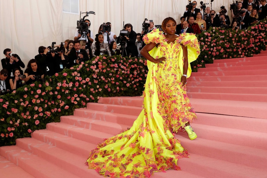 Serena Williams in a yellow gown with neon Nike trainers/