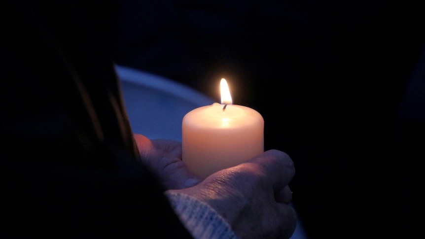 A candle being held by a pair of hands.
