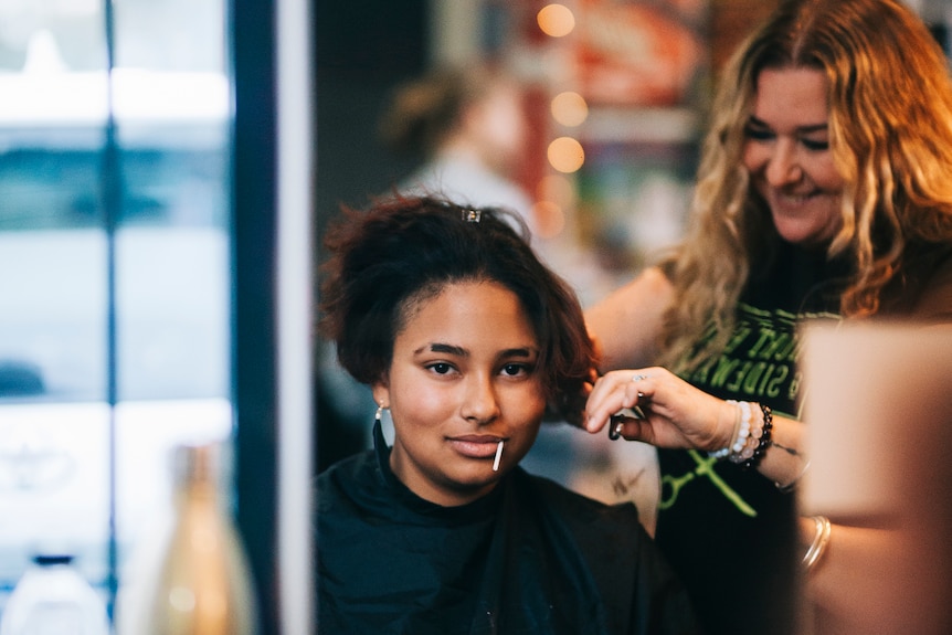 Woman looks in the mirror as her hair is cut.