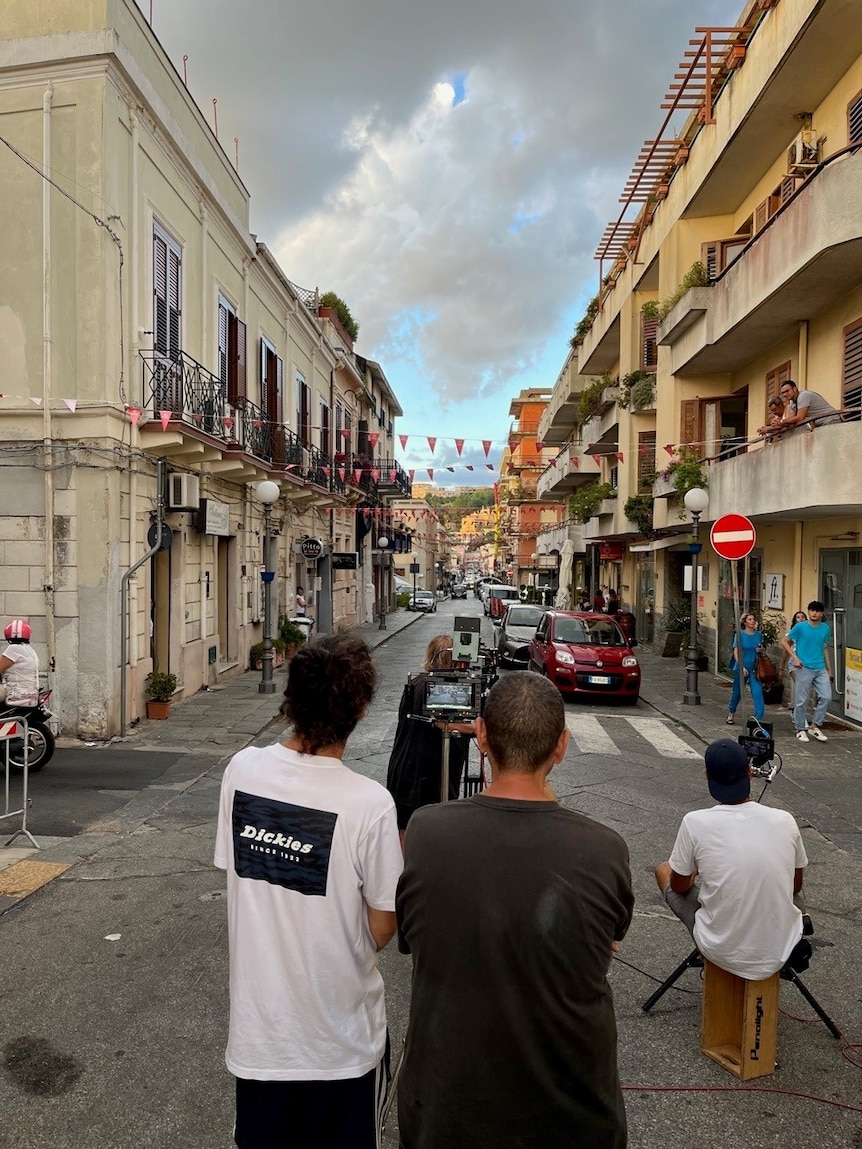 Camera crew filming in narrow Italian street.