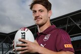 Kalyn Ponga poses for a promo shot, wearing a Maroons polo and holding a football