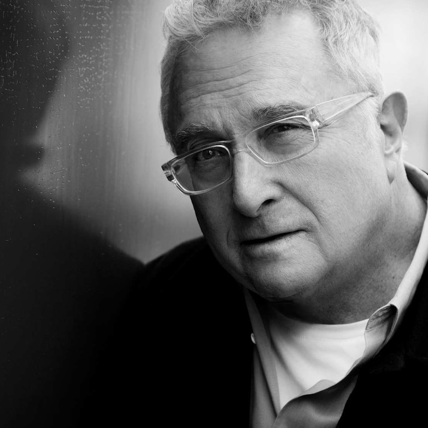 Black and white image of Randy Newman with glasses, looking at the camera