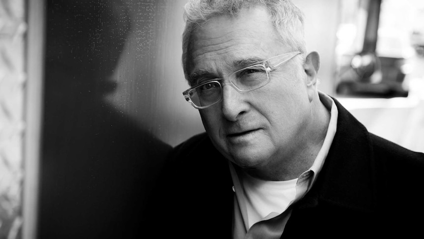 Black and white image of Randy Newman with glasses, looking at the camera