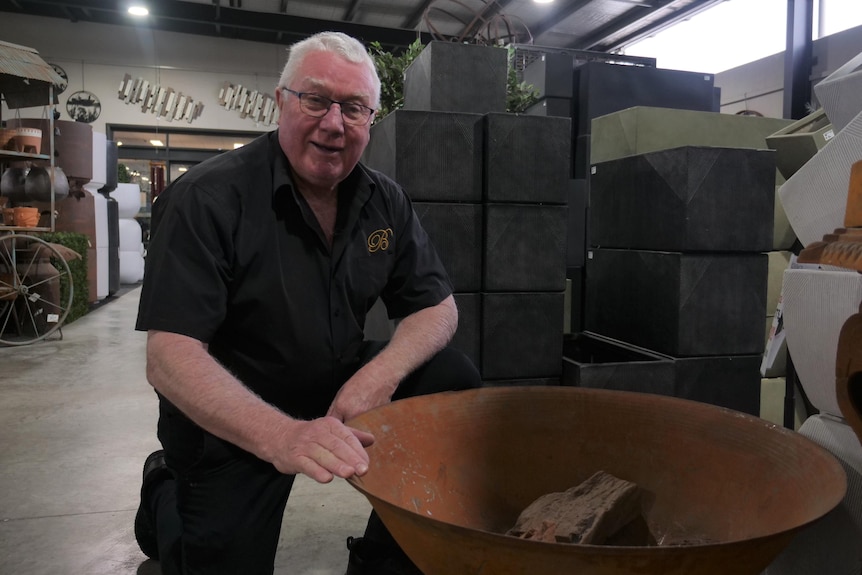 A man smiles over a fire pit in a shop