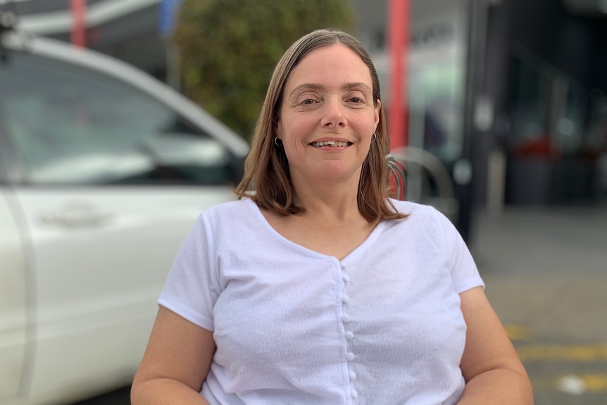 A woman in a white top seated in a wheelchair.