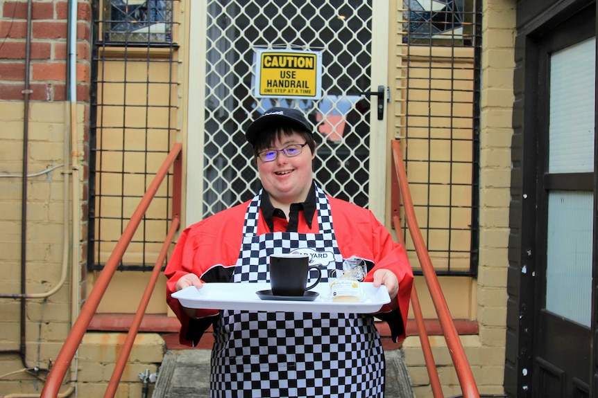 Angela with a tray in the backyard of the cafe