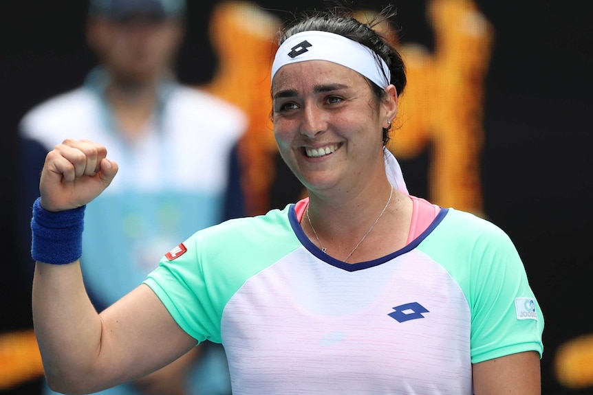 A female tennis player smiles after winning a match at the Australian Open.