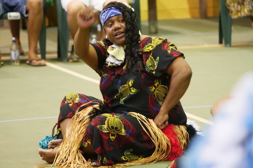 Woman sits on floor dancing