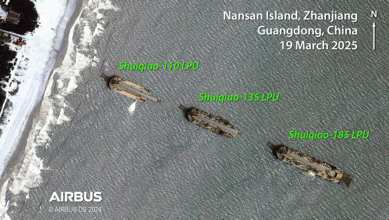 A satellite photo of three landing barges forming one line in close proximity to a beach in China