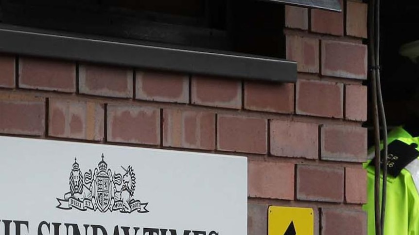 A policeman walks through the security gates in front of a News Of The World sign (Getty Images: Peter Macdiarmid)