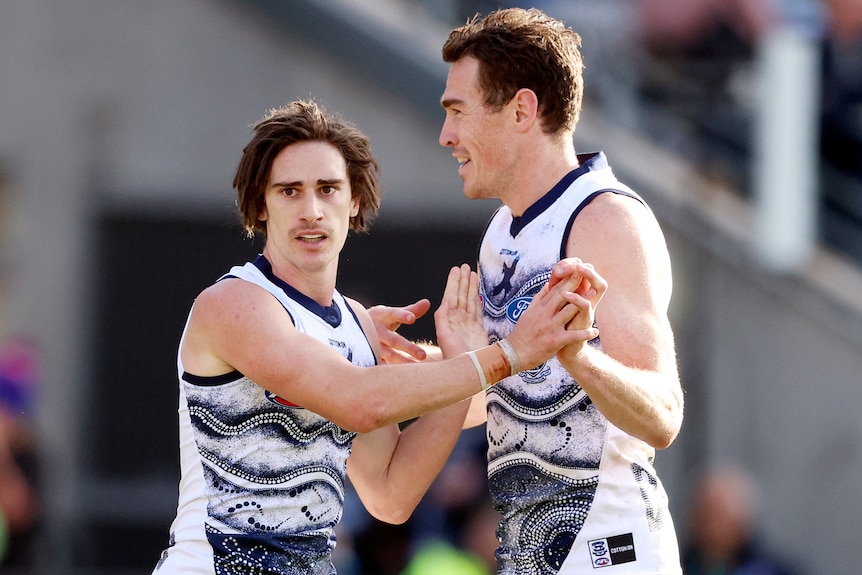 Two Geelong AFL players celebrate a goal against the Adelaide Crows.