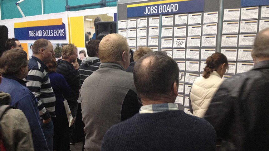 People check jobs board at a job expo.