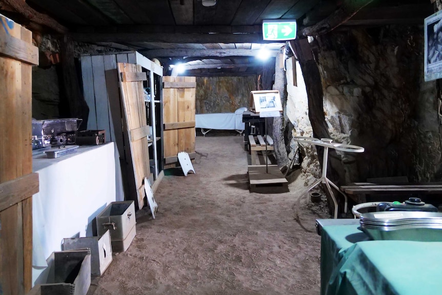 An image of an underground tunnel, with old furniture from the health profession.