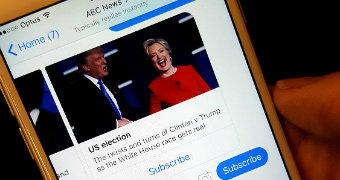 A close-up photo of a person holding a phone displaying a message from ABC News on Facebook Messenger.