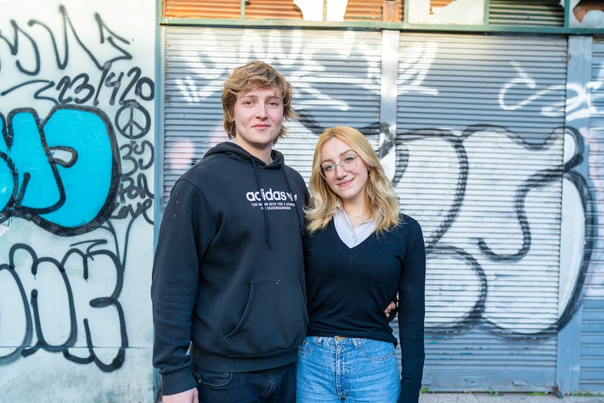 Two people in front of graffiti.