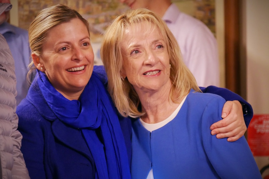 Two women wearing blue embrace eachother
