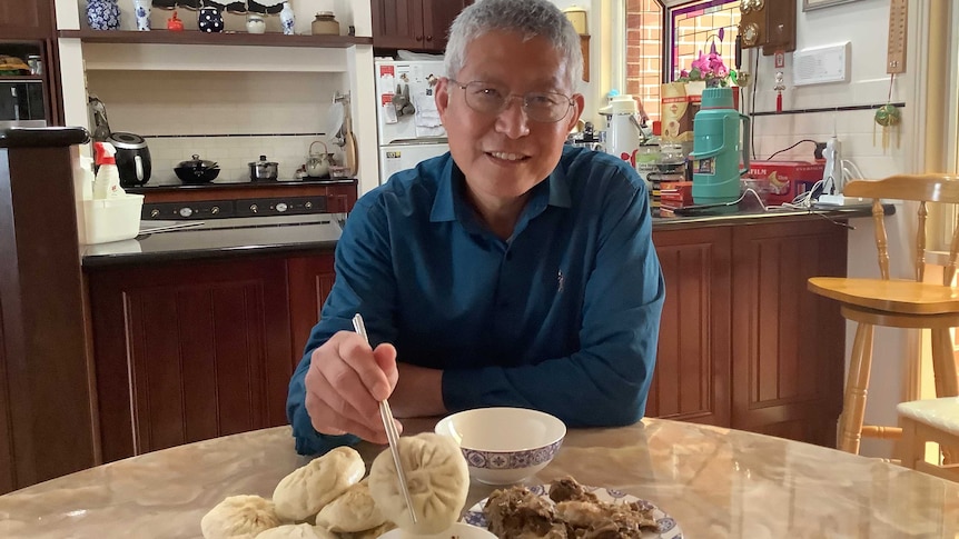 Jianhua Zhang picks up a bun with his chopsticks.