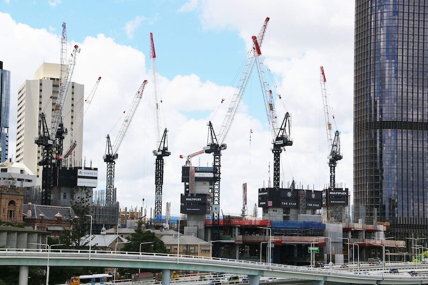 Construction cranes at Queens Wharf development in Brisbane's CBD with 1 William Street building and Riverside Expressway.