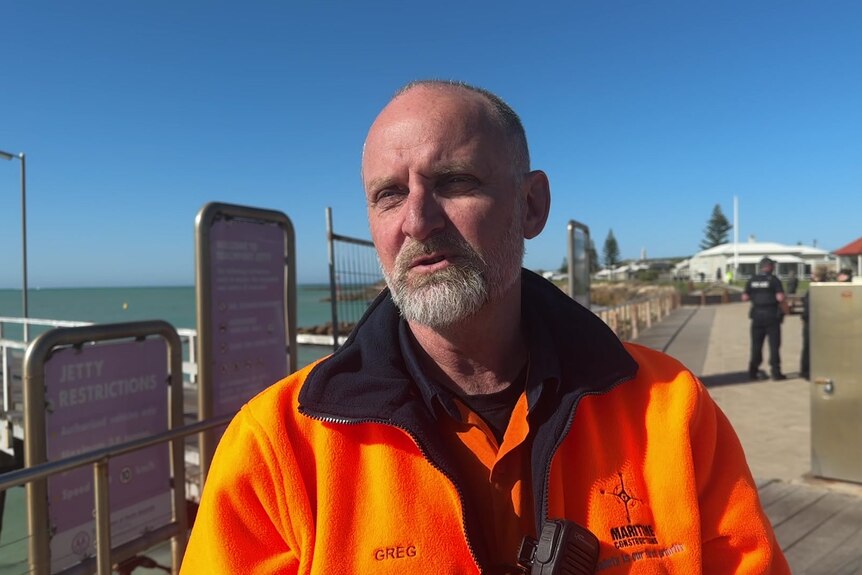 A worker in hi-vis clothing near a jetty.