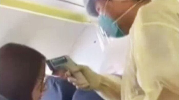 Video still circulating on Chinese social media shows a medic checking temperatures of a passenger on Wuhan to Macao flight.