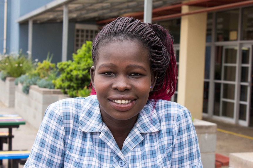 Sudanese teenage girl in school uniform outside school