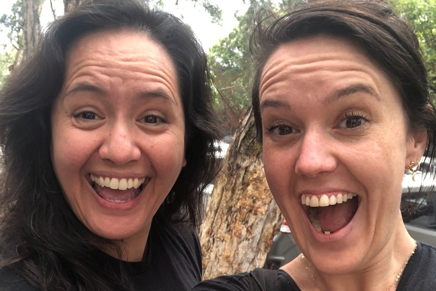 Two women smile excitedly for a selfie.
