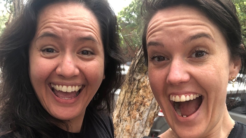 Two women smile excitedly for a selfie.