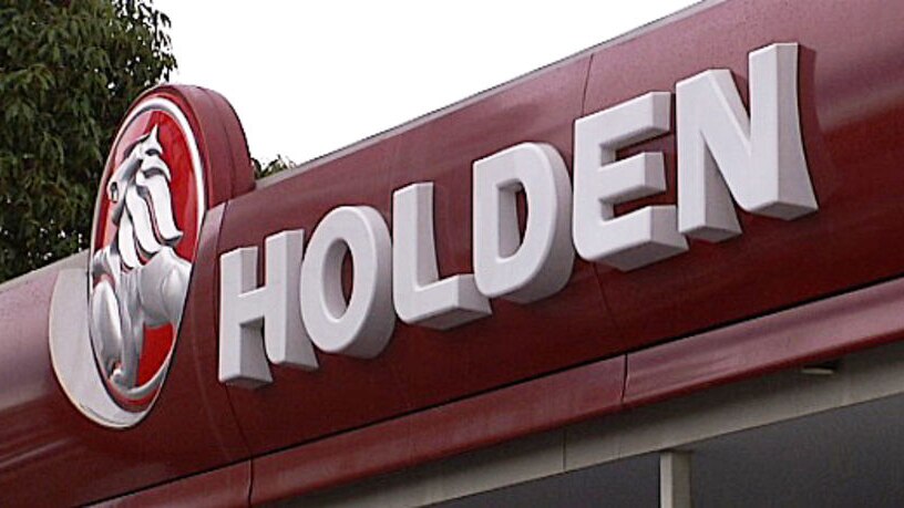 A sign and logo for Holden on the front of a car yard.