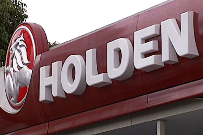 A sign and logo for Holden on the front of a car yard.