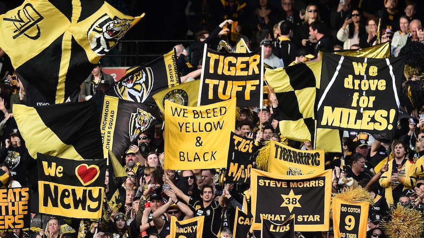 Richmond fans hold up yellow-and-black flags and banners at the MCG.