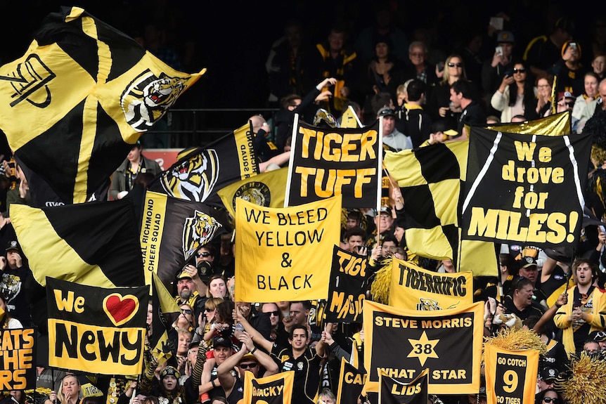 Richmond fans hold up yellow-and-black flags and banners at the MCG.