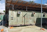 The rear of the Delta Compound on Manus Island: a run down green building with patches of rust.