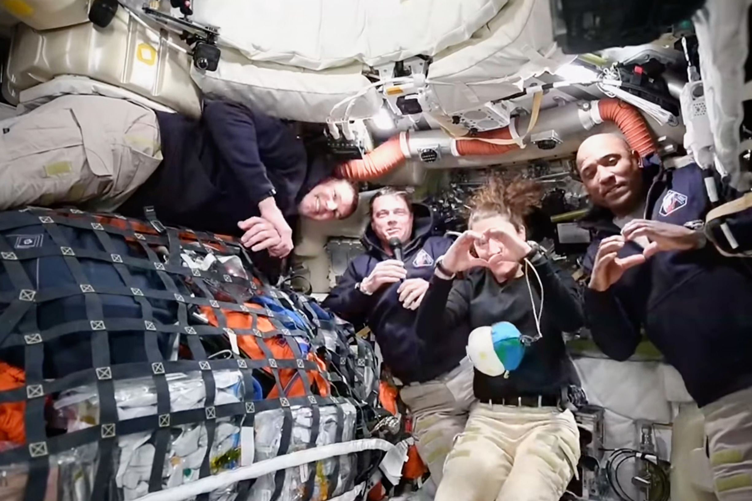 Four astronauts pose for a photo inside a spacecraft