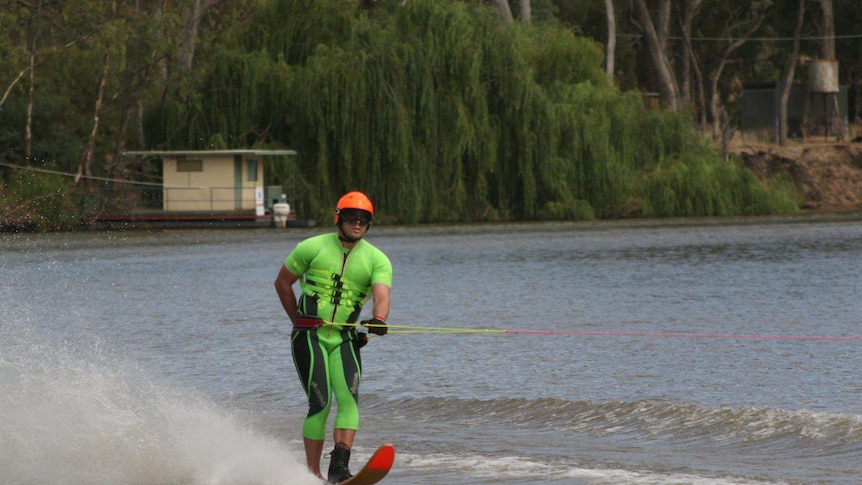 Ben Pettingill water skiing in a green wetsuit