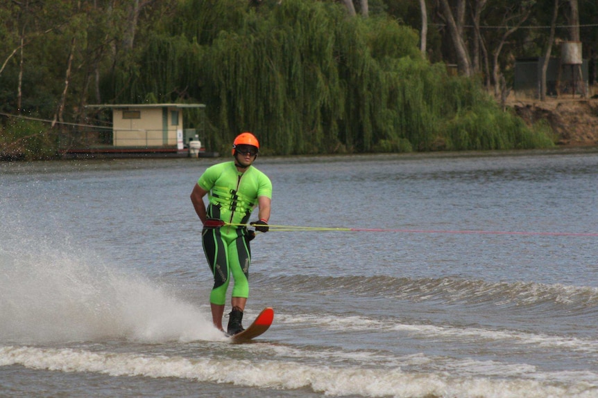 Ben Pettingill water skiing in a green wetsuit