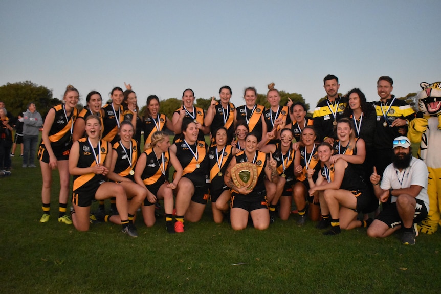 A happy team of female AFL players.