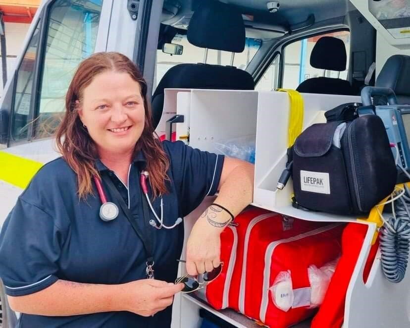 A woman smiling and leaning on some medical equipment 