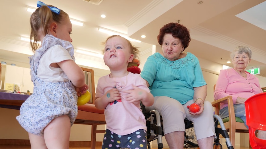 Two kids and two aged care residents play together.