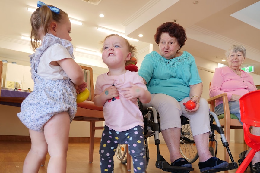 Two kids and two aged care residents play together.