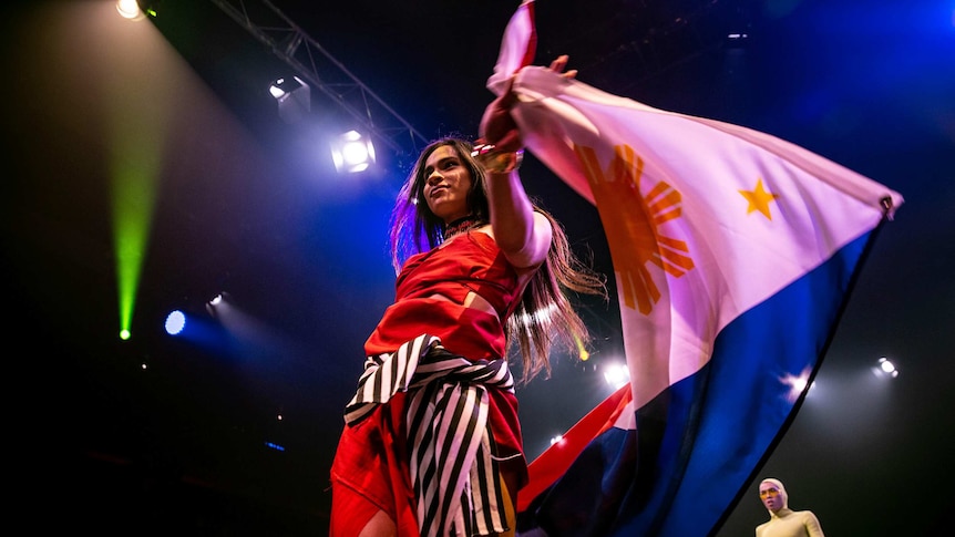 A vogue performer in red outfit and carries Philippines flag on the runway at Sissy Ball 2019.