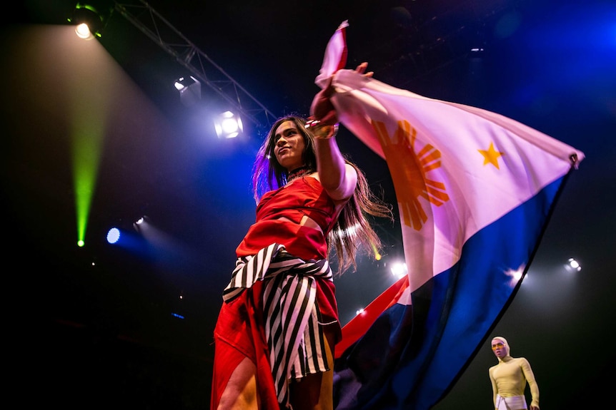 A vogue performer in red outfit and carries Philippines flag on the runway at Sissy Ball 2019.