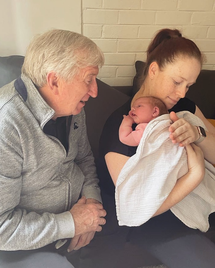 Erin sitting next to her dad and holding her young daughter close to her chest.