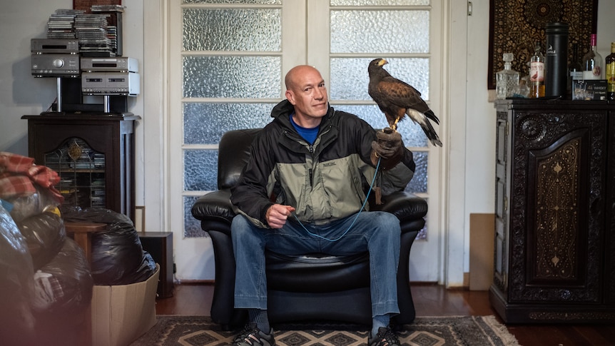 Kenny Pinnock in his living room hold his falcon Jacques.