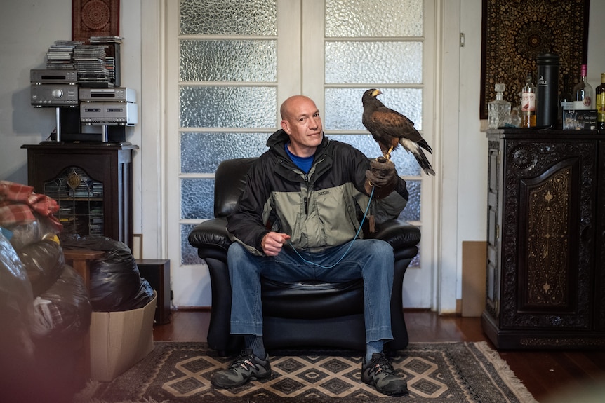 Kenny Pinnock in his living room hold his falcon Jacques.