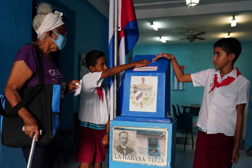 Two children standing next to a blue ballot box in a Cuban referendum to vote for same-sex marraiges. 