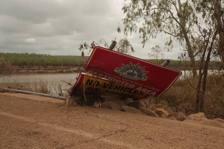 A sign reading "Australian Defence Force restricted area" is shown knocked over on the ground. 