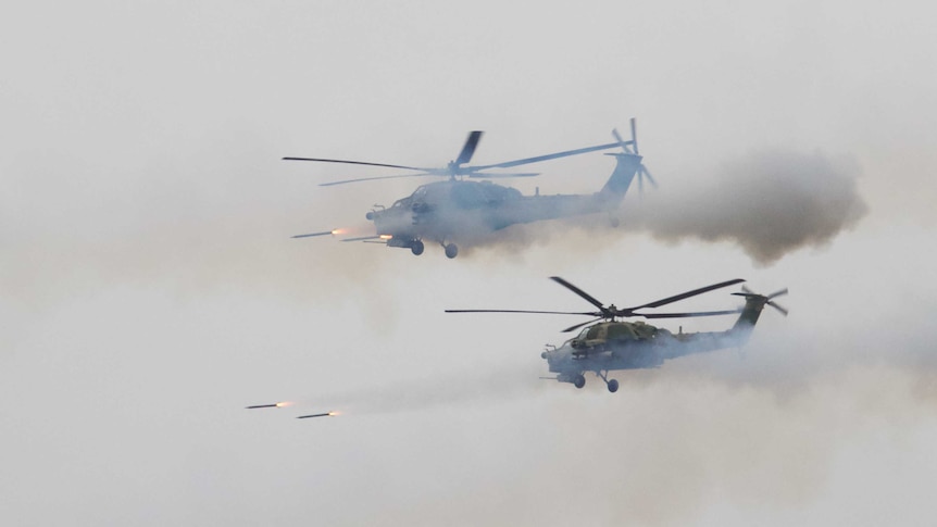 Missiles are seen being fired from two helicopters in mid flight.