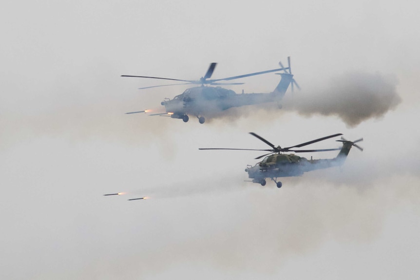 Missiles are seen being fired from two helicopters in mid flight.