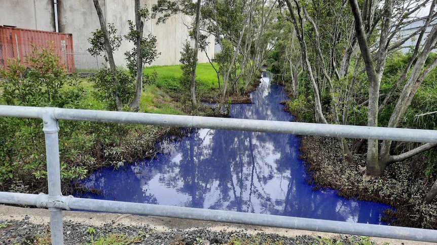 a small creek in an industrial area with blue water